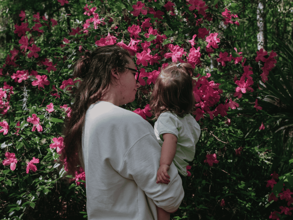 The author holding her daughter while appreciating the beauty of pink azaleas.