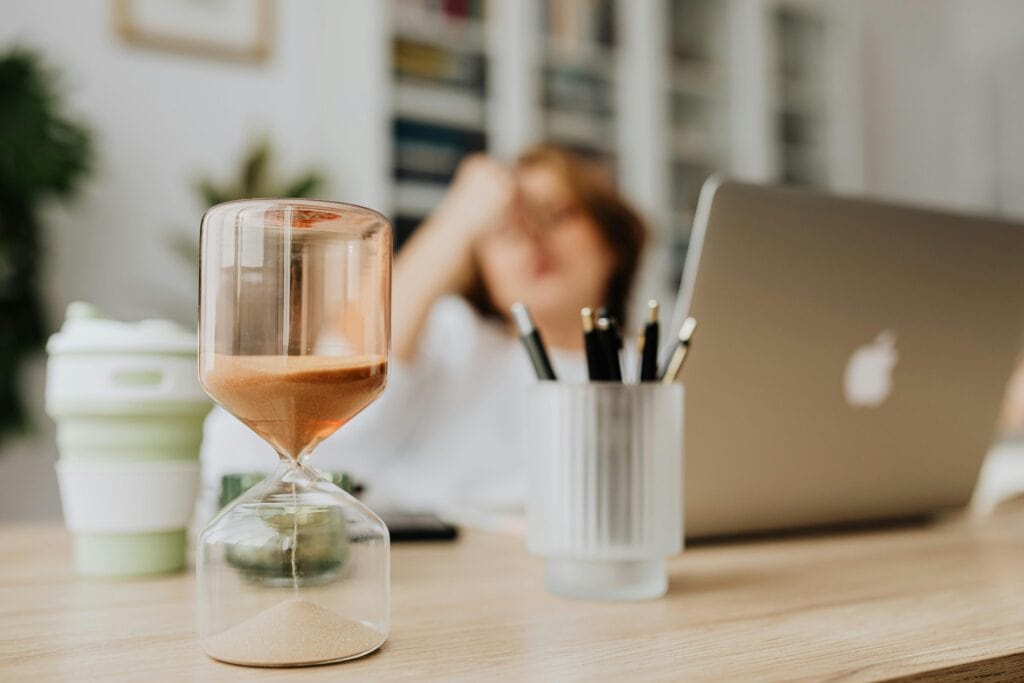 hourglass in home office representing quick meetings as a time-saving hack